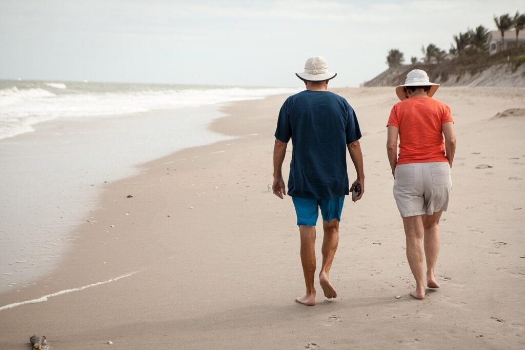 Senior couple walking together on a sandy beach, symbolizing financial security, peace of mind, and enjoying retirement through smart planning.