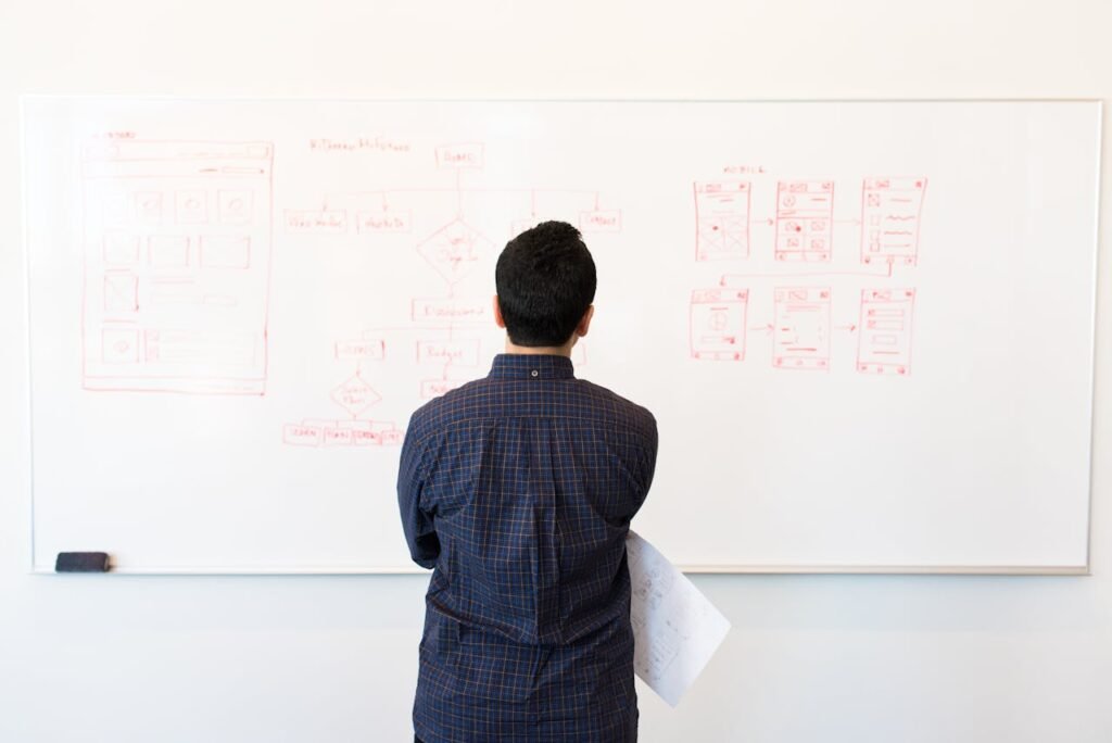 Man standing in front of a whiteboard with diagrams, planning and analyzing strategies, symbolizing steps to improve a credit score.