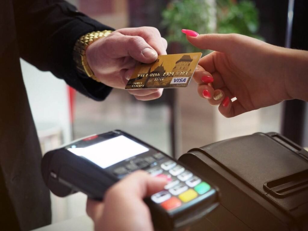 Customer handing over a Visa credit card for payment at a card reader.
