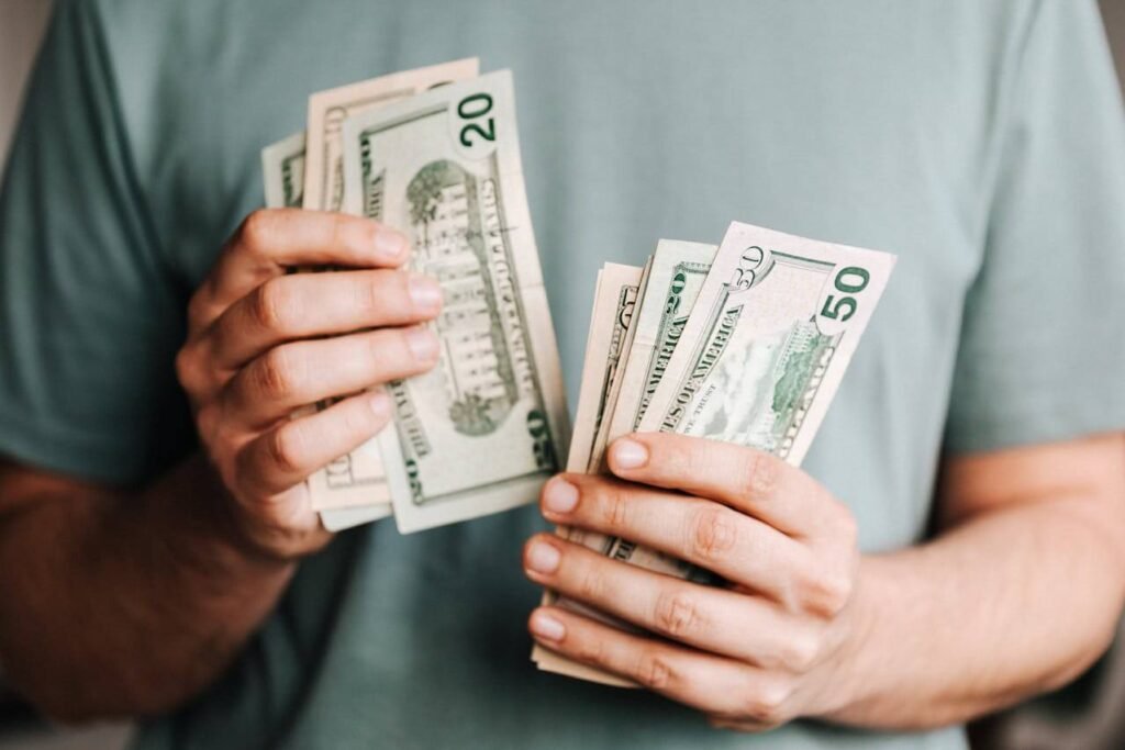 Person counting U.S. twenty- and fifty-dollar bills, showing careful money management.