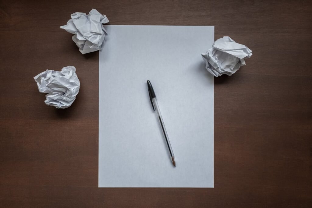 Blank sheet of paper with a pen surrounded by crumpled drafts, symbolizing common retirement planning mistakes and the importance of avoiding them.